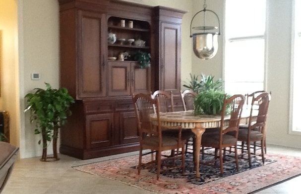 Dining room with sheaves of wheat chair backs and hand blown glass vessel.